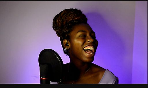 Aluna cantando ao microfone durante uma aula de canto da TOCA+