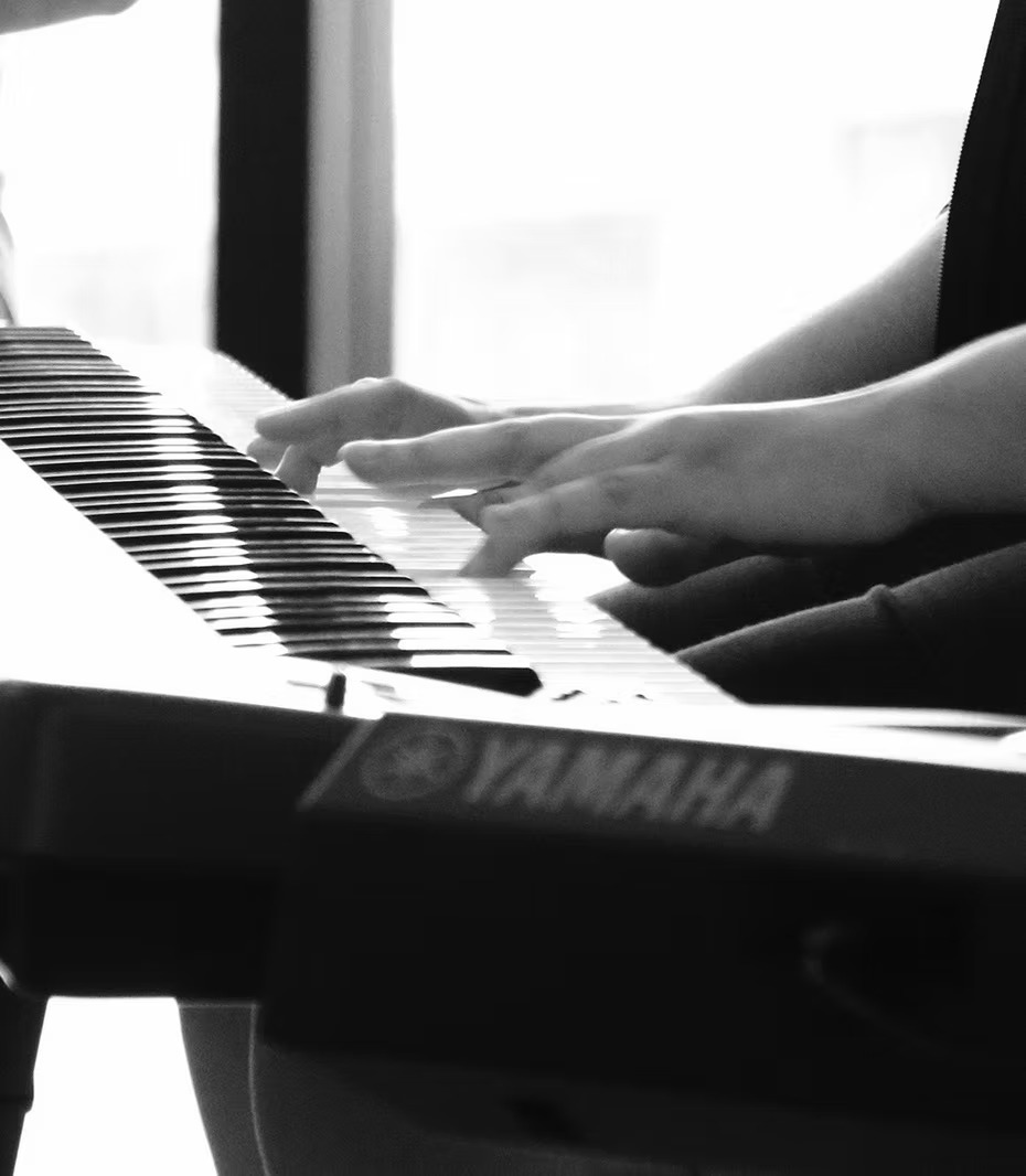 Mãos tocando teclado durante uma aula de piano da TOCA+